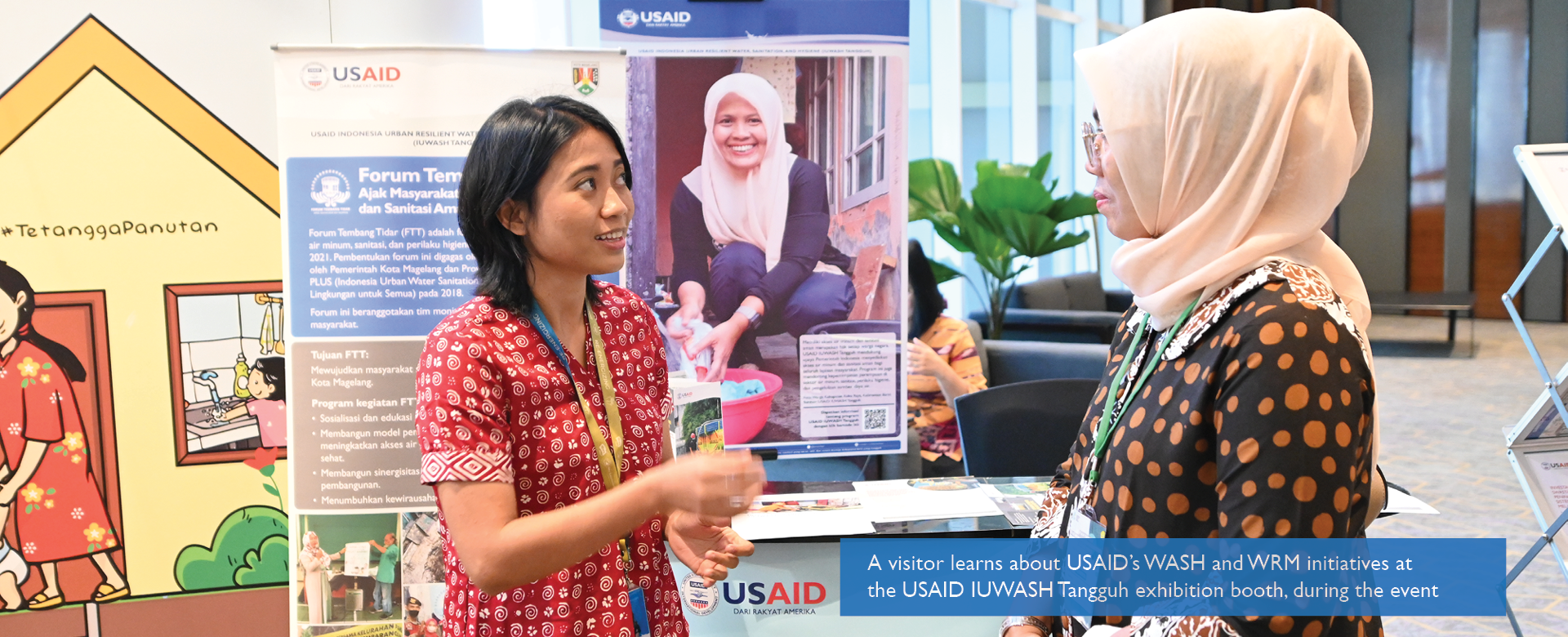 A visitor learns about USAID’s WASH and WRM initiatives at the USAID IUWASH Tangguh exhibition booth, during the event